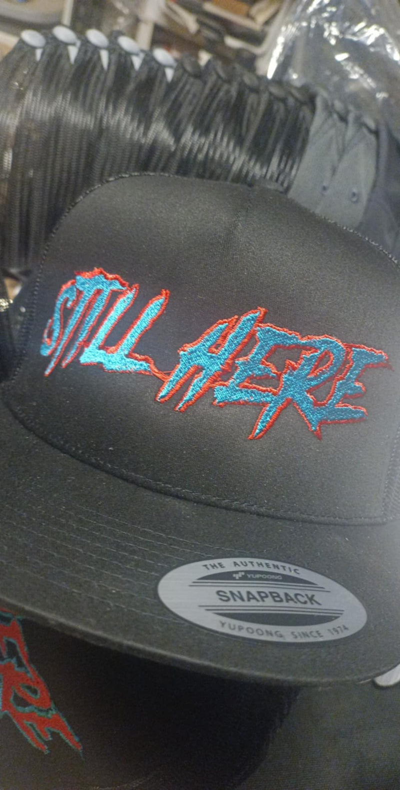 STILL HERE turquoise text snapback cap